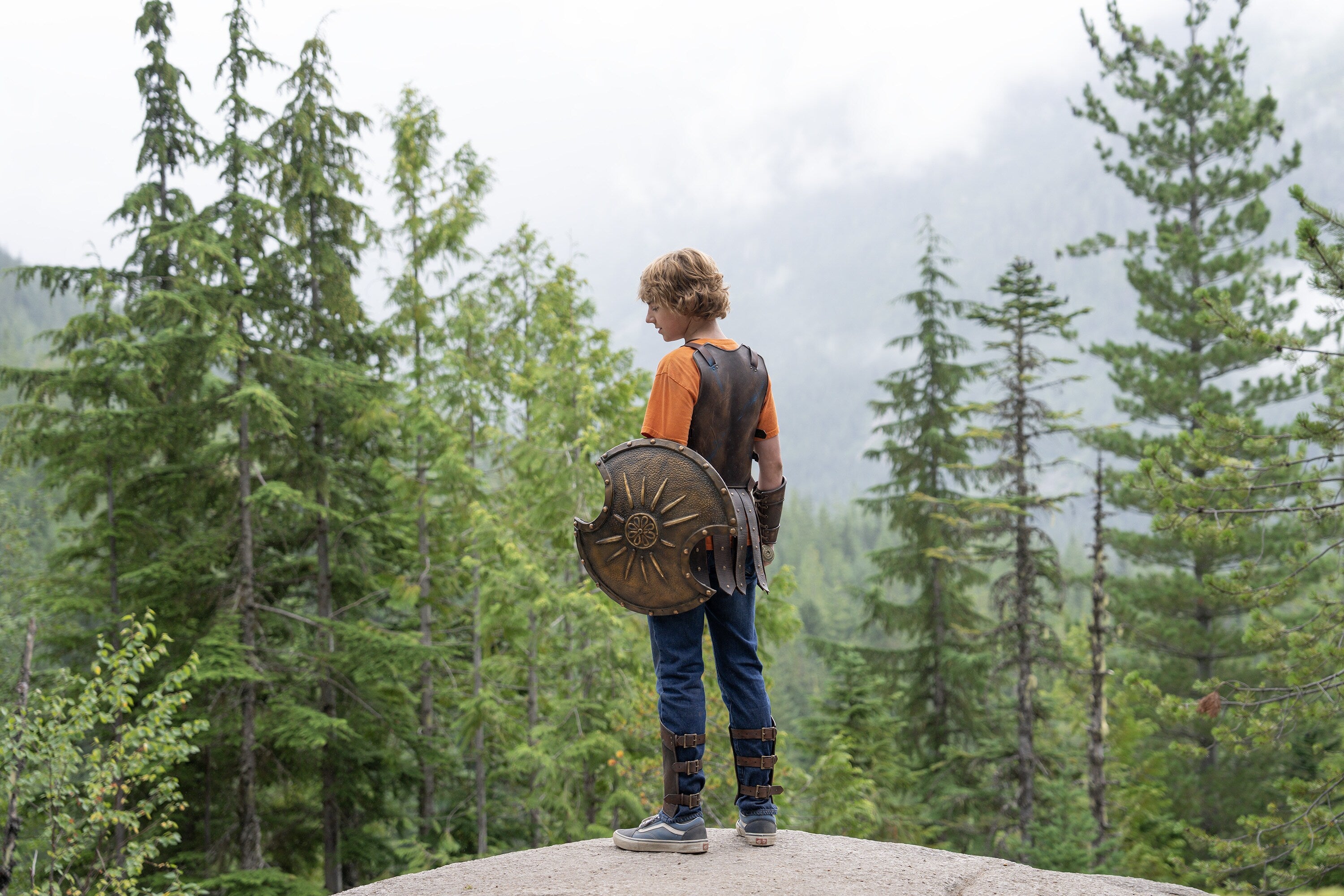 Promotional image of Percy Jackson wearing some armor and carrying a shield