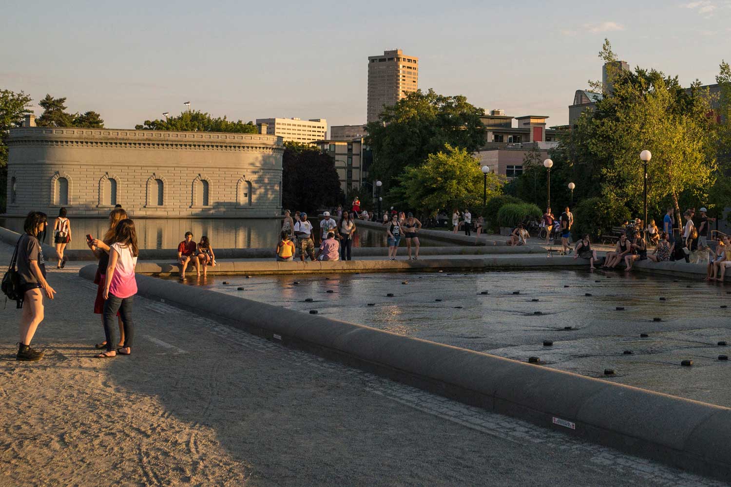 A photograph of Cal Anderson park at dusk, with people standing near the reflection pool