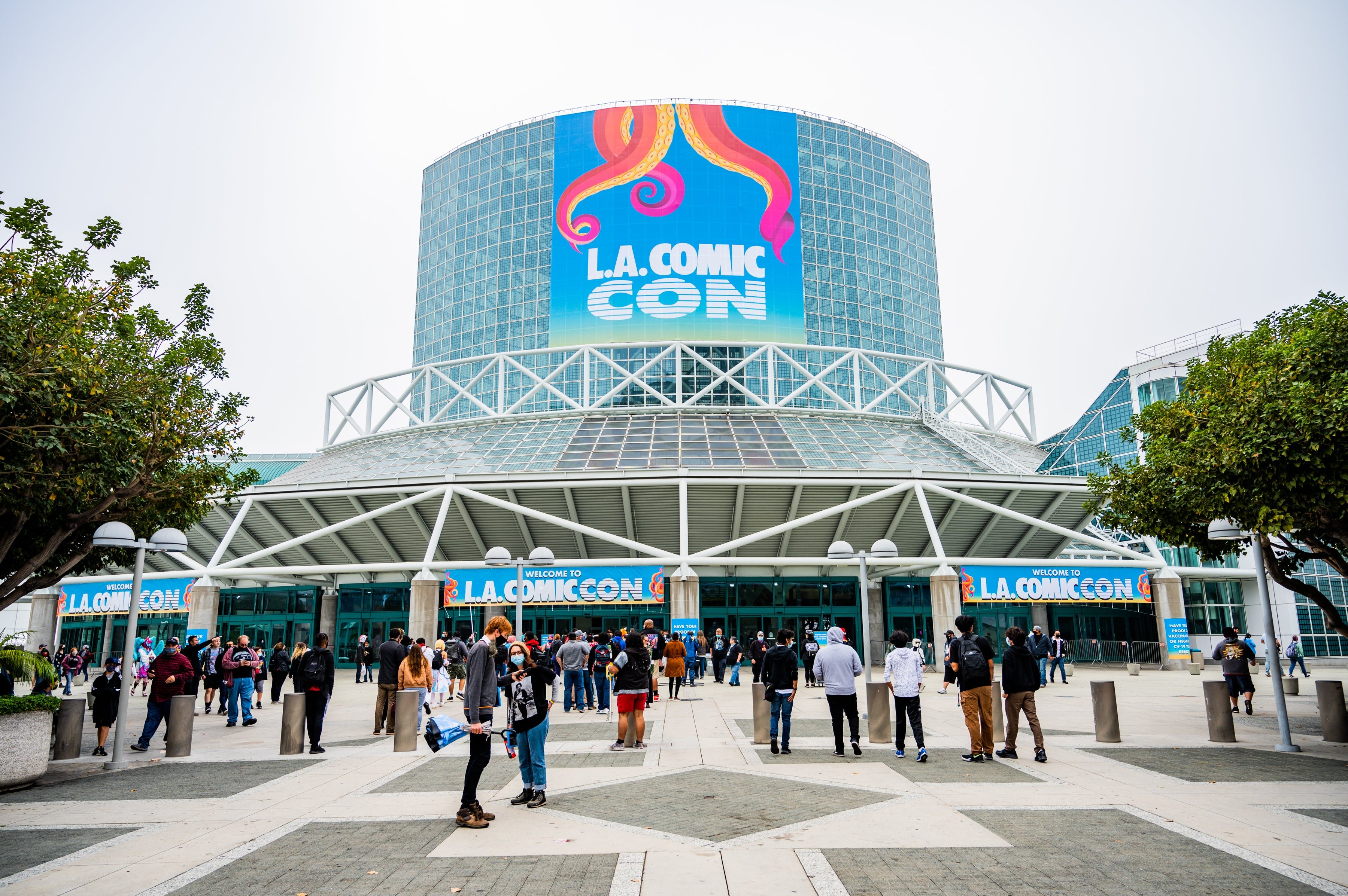 An outdoor photo of LA Comic Con featuring a banner and people