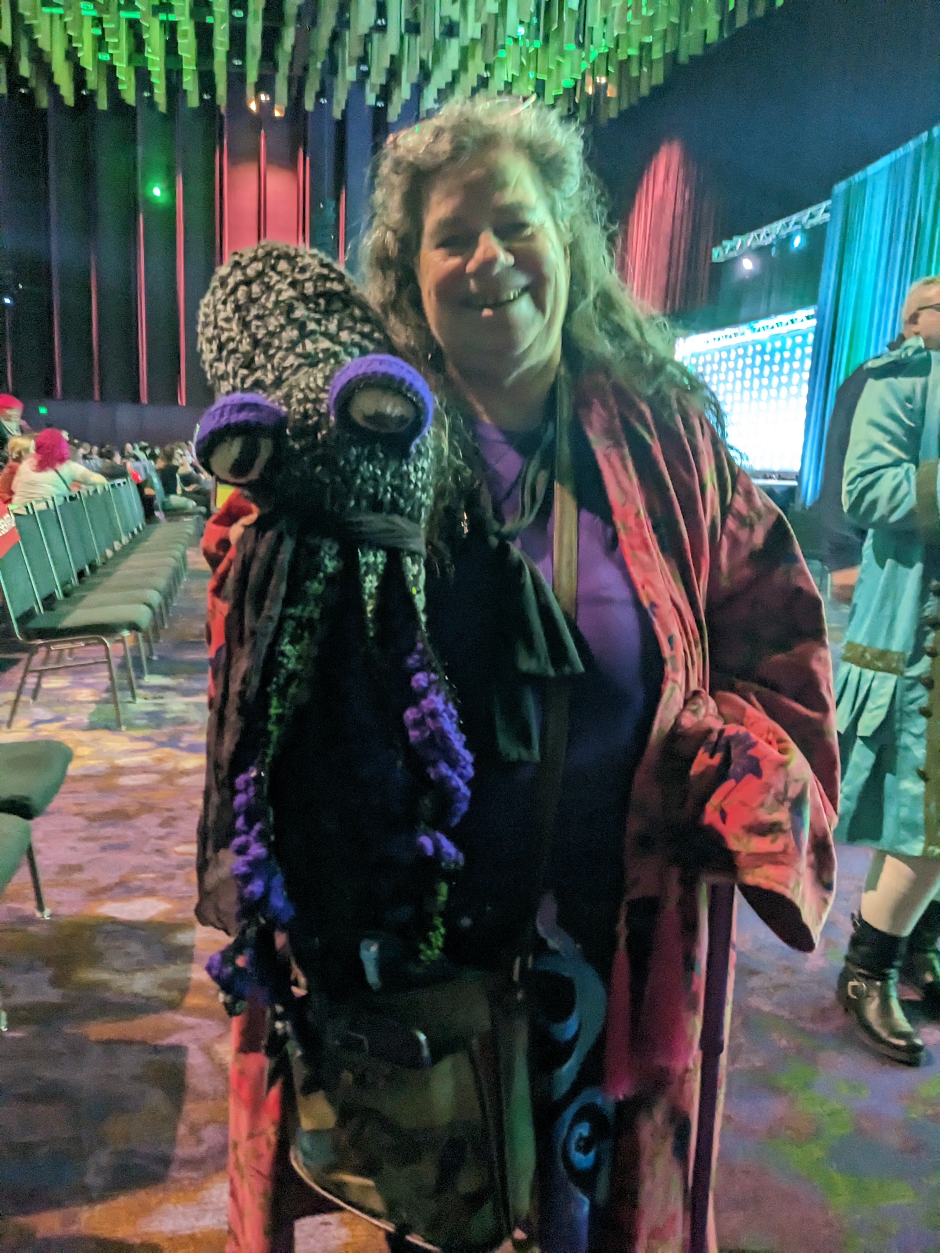 Woman wearing a red robe and holding a large crocheted cephalopod